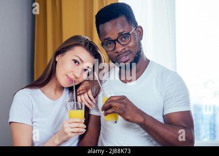 african american man with asian woman making smoothie at home, useing eco tubes from metall Stock Photo