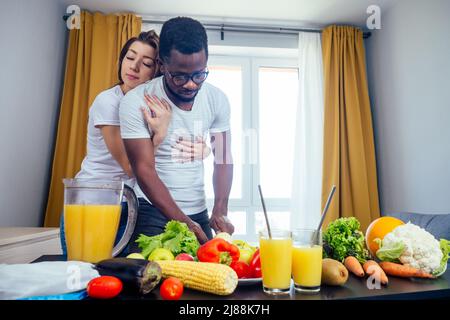 african american man with asian woman making smoothie at home, useing eco tubes from metall Stock Photo