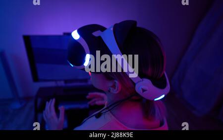 Woman interacts with virtual reality using a vr headset. Concept of virtual reality, futuristic entertainment and communication. Stock Photo