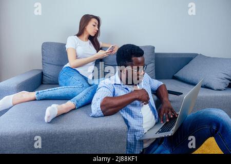 woman taking selfie photo on smartphone camera or video chatting,her african american man use laptop .home Internet wi-fi Stock Photo