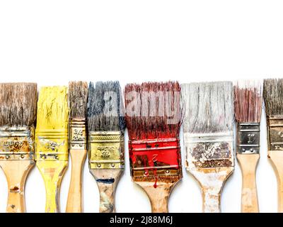 Used and dried paint brushes laid in a row shot from above on white Stock Photo