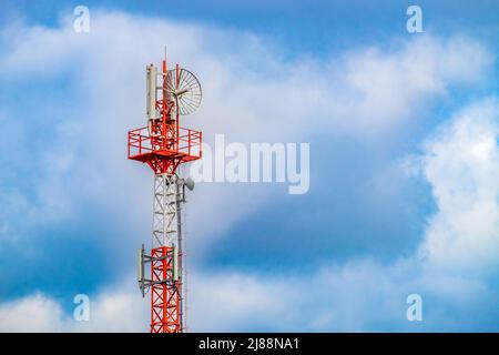 Radio mast (tower) with antennas for telecommunications and broadcasting and cloudy sky. Close-up Stock Photo