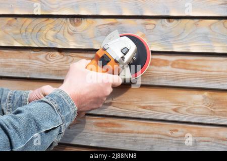 Man holds electrical grinder in his hands and sands the boards Stock Photo