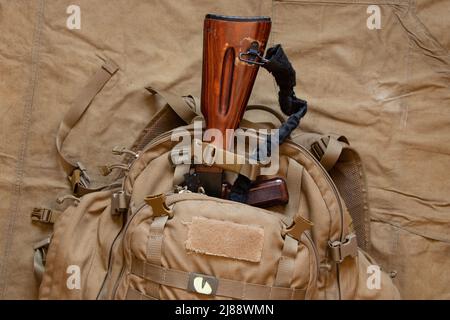 Military green backpack with a machine gun on a green background, backpack of a Ukrainian soldier, war in Ukraine Stock Photo