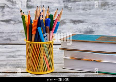 https://l450v.alamy.com/450v/2j890je/yellow-pen-holder-with-stack-of-books-on-white-desk-back-to-school-concept-2j890je.jpg