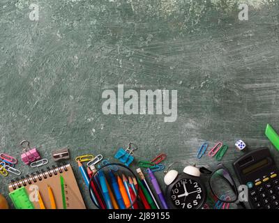 School background with school supplies and copy space. Top view, pens and pencils, notebooks, green chalk board Stock Photo