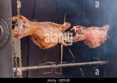 Process of cooking ram carcasses on spit at summer street food market ...