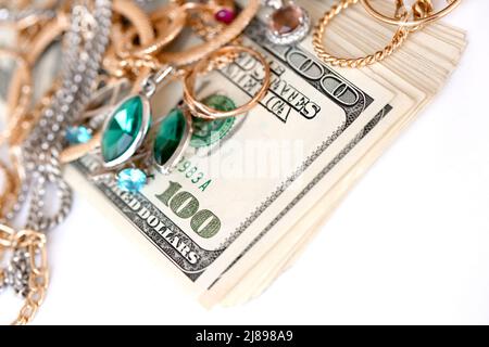 Many expensive golden and silver jewerly rings, earrings and necklaces with big amount of US dollar bills on white background. Pawnshop or jewerly sho Stock Photo