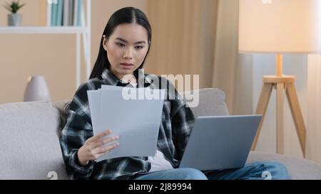 Asian busy concentrated business woman freelancer girl student house owner householder female with paper documents checking budget financial Stock Photo