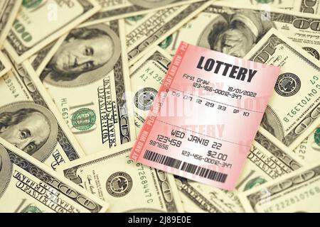 Red lottery ticket lies on big amount of hundred dollar bills. Lottery playing concept or gambling addiction. Close up photo Stock Photo