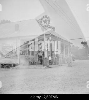 Rural filling station becomes community center and general grounds for loafing. The men in baseball suits are on a local team which will play a game nearby. The team is called the Cedargrove Team. Fourth of July, Near Chapel Hill, North Carolina. Stock Photo