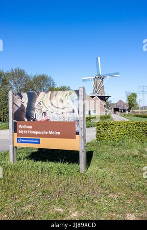 Stevensweert, South Limburg, Netherlands, April 16, 2022. Huge sign saying Welcome to Hompesche Molen, footpath, bushes and a Dutch windmill in the ba Stock Photo