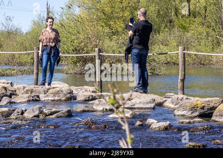 Stevensweert, South Limburg, Netherlands, April 16, 2022. Tourist couple taking a photo on the steps of Brug Molenplas in the Oude Maas river, sunny d Stock Photo