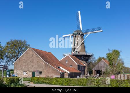 Stevensweert, South Limburg, Netherlands, April 16, 2022. Dutch windmill Hompesche Molen next to a building, a restaurant, a small terrace surrounded Stock Photo