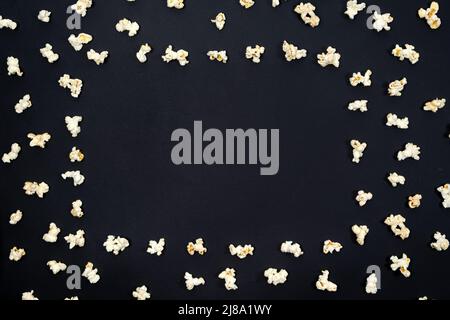 Popcorn scattered in the form of a frame on a black background, top view, space for text. Stock Photo