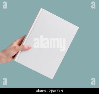 Hand holding empty book mock up over minimal background. High quality photo Stock Photo