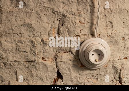 socket with a wire on an old white brick retro wall. loft interior concept Stock Photo