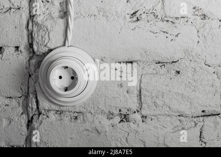 socket with a wire on an old white brick retro wall. loft interior concept Stock Photo