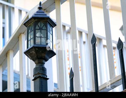 An old-fashioned street lamp on a metal fence. Summer day. Stock Photo