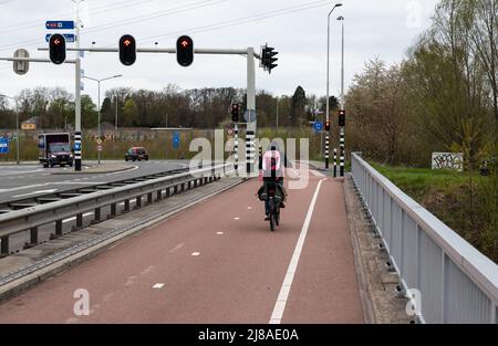 Maastricht, Limburg - The Neteherlands - 04 05 2022 - Mother driving a bike over a double laned path over the highway bridge Stock Photo