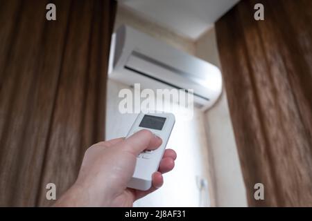Split air conditioner on a wall. Turning on conditioner on summer day. Stock Photo