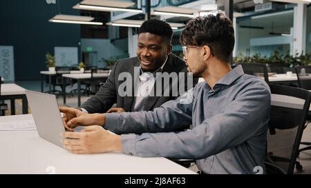 Arabian man financial analyst explain business strategy African entrepreneur pointing on laptop discussing startup reviewing project contract benefits Stock Photo