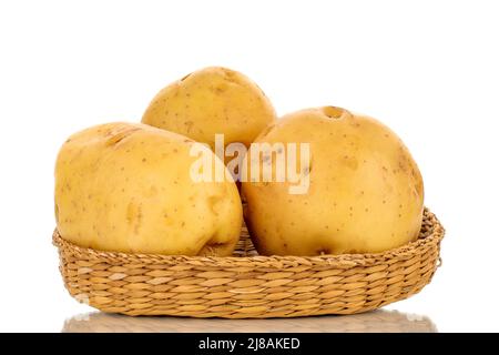 Three raw organic potatoes on a straw plate, close-up, isolated on a white background. Stock Photo