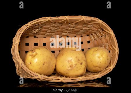 Three raw organic potatoes with a basket, close-up, isolated on a black background. Stock Photo