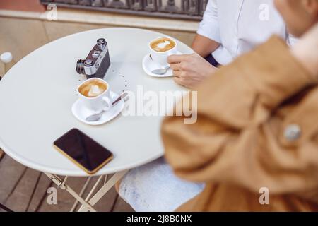 Close-up of man and lady sitting at table with cups of coffee Stock Photo