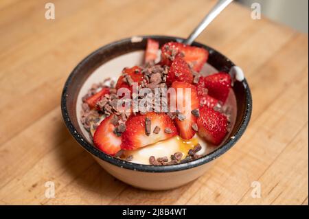 Strawberries in little bowl on yogurt and topped with cocoa nibs Stock Photo