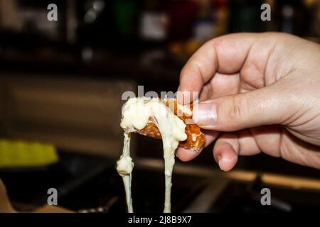 Georgian khachapuri - hand holding a piece of the bread torn off the bowl dripping with melted cheese Stock Photo