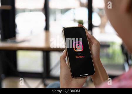 CHIANG MAI, THAILAND - MAY 14 2022: Woman holding iPhone 13 Pro Max with Instagram application on the screen. Instagram is a popular online social Stock Photo