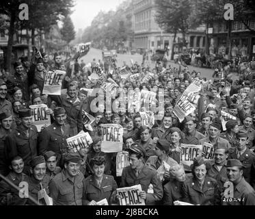 US military personnel celebrating VJ (Victory in Japan) Day in Paris. Many are holding the front page of The Stars and Stripes newspaper with the word Peace as the headline. Stock Photo