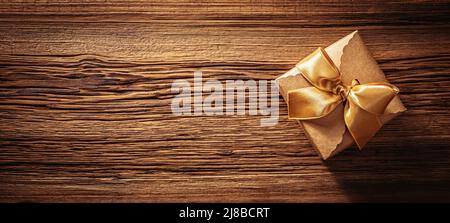 Kraft paper gift box with gold ribbon bow on old wood texture Stock Photo