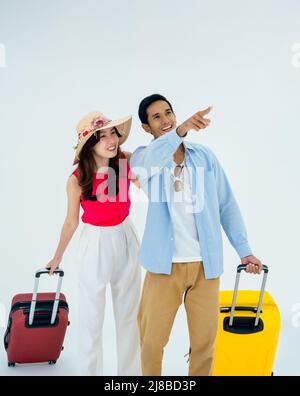 Exciting travel, happy holiday. Summer vacation. Asian couple travelers looking out with exciting, young man and woman pointing and walking with suitc Stock Photo