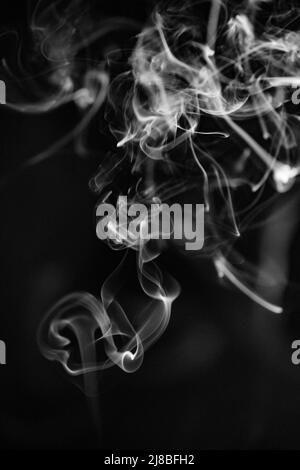 Black and white swirling, ascending smoke pattern on a black background, photo could be used as a background, smoke texture, abstract, or general stoc Stock Photo