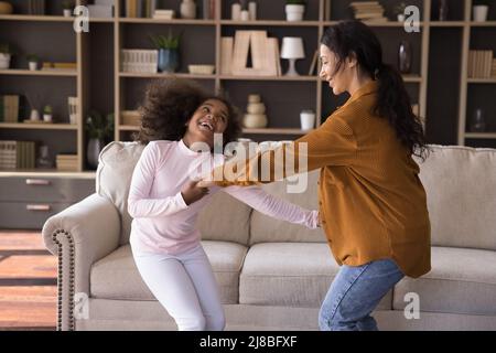 Cute little girl and mother holding hands dancing at home Stock Photo