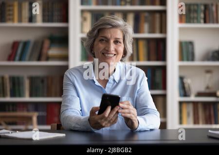 Happy mature business professional woman holding mobile phone Stock Photo