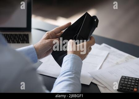 Hand of retired woman opening empty wallet at work table Stock Photo