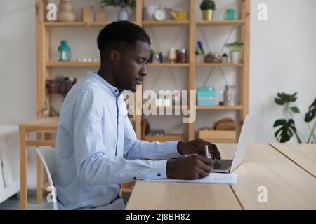 Focused Black student guy watching learning webinar on laptop Stock Photo