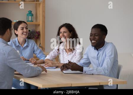 Cheerful excited diverse business team brainstorming at meeting table Stock Photo