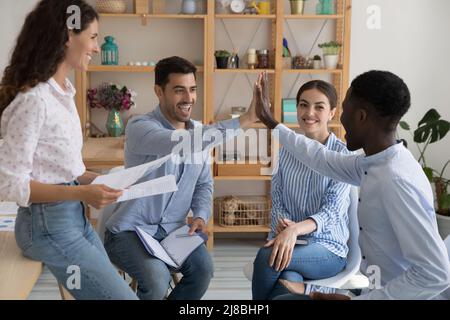 Happy diverse interns, employees celebrating business team success Stock Photo