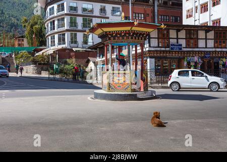 Thimphu, Bhutan - October 26, 2021: Crossroads in Thimphu. Policeman regulates the traffic. Traditional crossing hut to protect the policeman. Dog lie Stock Photo