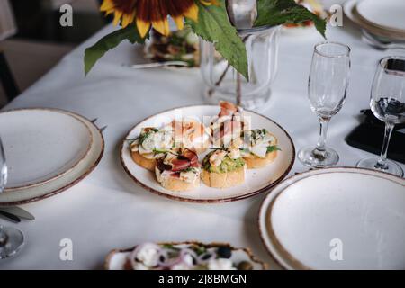 Delicious bruschettas with different ingredients on a white plate. Guacamole with shrimp, prosciutto, salmon and dorblu cheese. Outdoor feast on Stock Photo