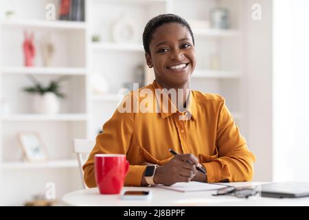 Portrait of happy young black woman working at office Stock Photo