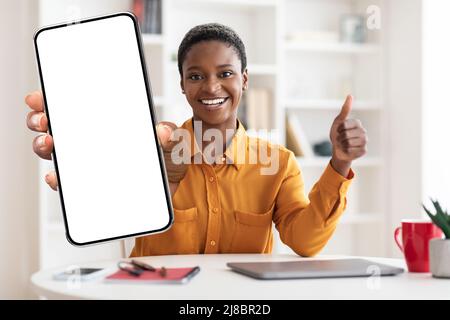 Smiling black woman showing smartphone with empty screen, mockup Stock Photo