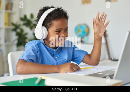 cheerful african american boy waving hand while sitting near parents ...