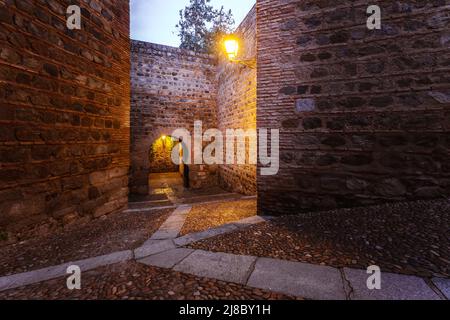 Narrow street. Rear view of Puerta de Alcantara, historical landmark in Toledo, Spain Stock Photo