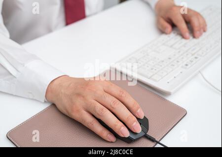 Hand of businessman holding computer mouse at office desk. Stock Photo