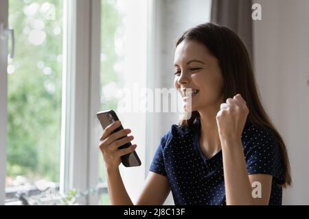 Joyful happy cellphone user girl feeling joy, getting good news Stock Photo